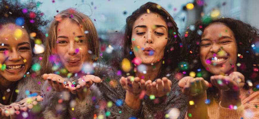 Young,Women,Blowing,Confetti,From,Hands.,Friends,Celebrating,Outdoors,In